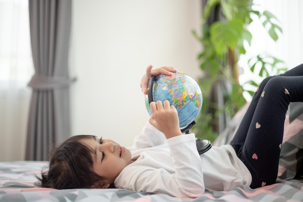 Bella ragazza che guarda un globo terrestre e impara la geografia