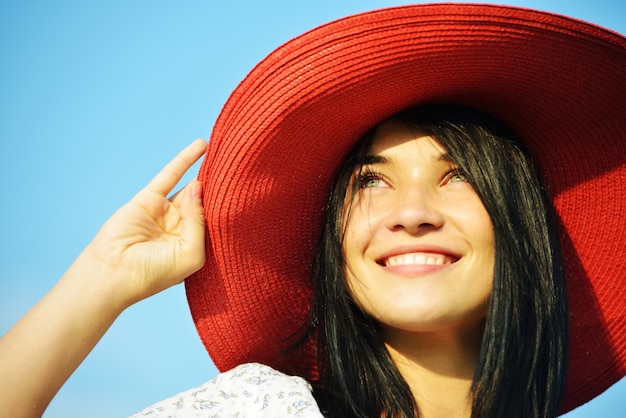 Bella ragazza che indossa il cappello rosso sul prato di estate