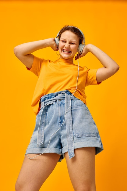 Bella ragazza che indossa le cuffie pantaloncini di jeans primo piano emozioni stile di vita inalterato