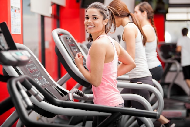 Bella ragazza che lavora su un tapis roulant in palestra e sorridente