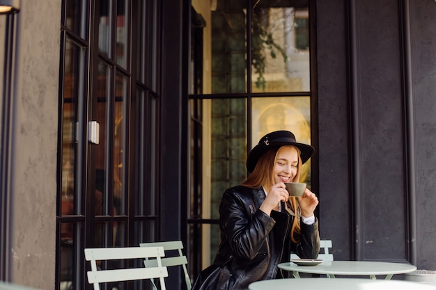 Bella ragazza che mangia caffè al caffè