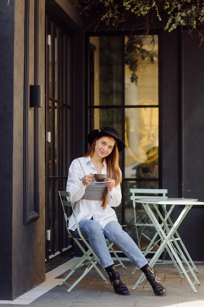 Bella ragazza che mangia caffè al caffè