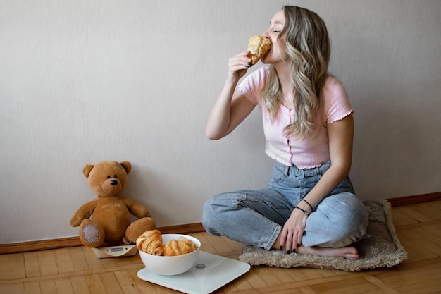 Bella ragazza che mangia i croissant a casa