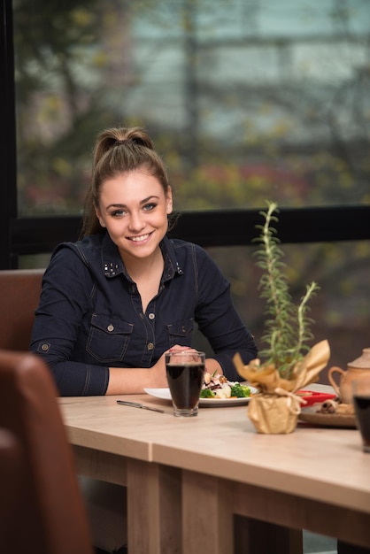 Bella ragazza che mangia in un ristorante e sembra felice