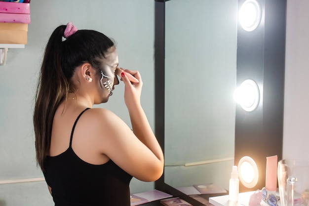 Bella ragazza che offusca il suo trucco di Halloween nella sua stanza.