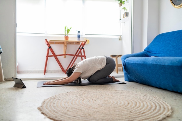 bella ragazza che pratica esercizio e yoga nel suo soggiorno con un gatto nero