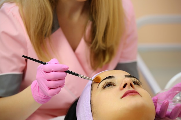 Bella ragazza che riceve procedura di pulizia facciale ad un cosmetologo.