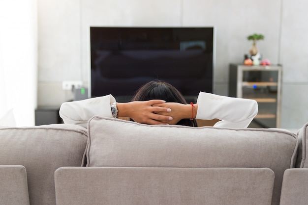 Bella ragazza che riposa e che guarda TV