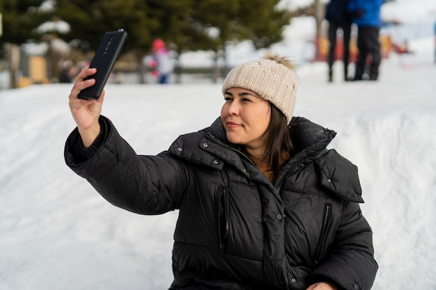 bella ragazza che scatta foto sulla neve mentre si diverte