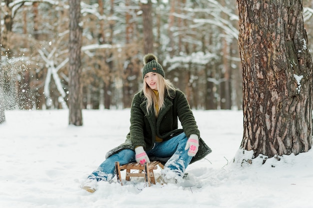 Bella ragazza che si gode l'inverno all'aperto Belle donne che si divertono con la neve e la slitta nella foresta