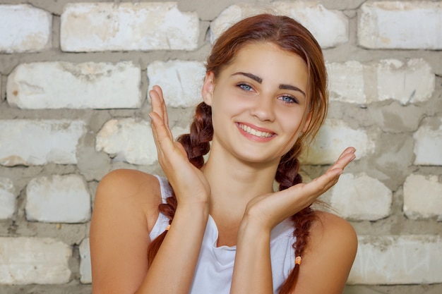 Bella ragazza che sorride con la felicità sul fondo del muro di mattoni