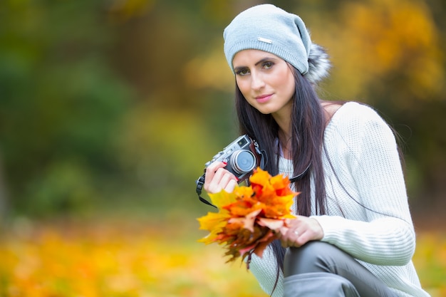 Bella ragazza che spara con la retro macchina fotografica nella giornata di sole autunnale