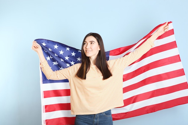 Bella ragazza che tiene la bandiera dell'america su uno sfondo colorato