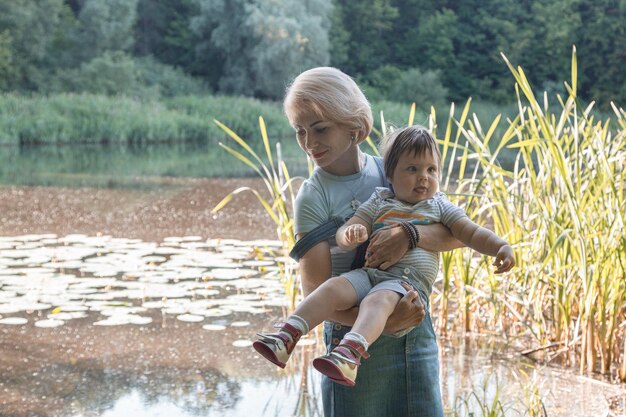 Bella ragazza che tiene un bambino in braccio sullo sfondo del lago