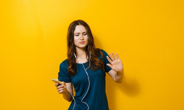 Bella ragazza che tiene un cellulare e che ascolta la musica nelle cuffie