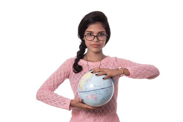 Bella ragazza che tiene un globo del mondo isolato su una parete bianca