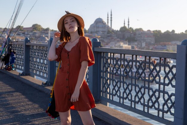 Bella ragazza con abito color arancio in posa con il ponte di Galata e le moschee di Istanbul