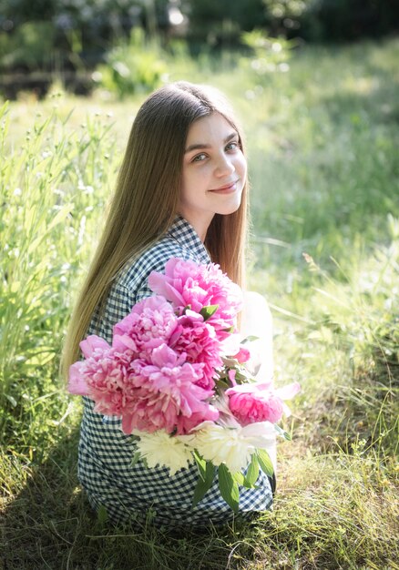 Bella ragazza con bouquet di peonie