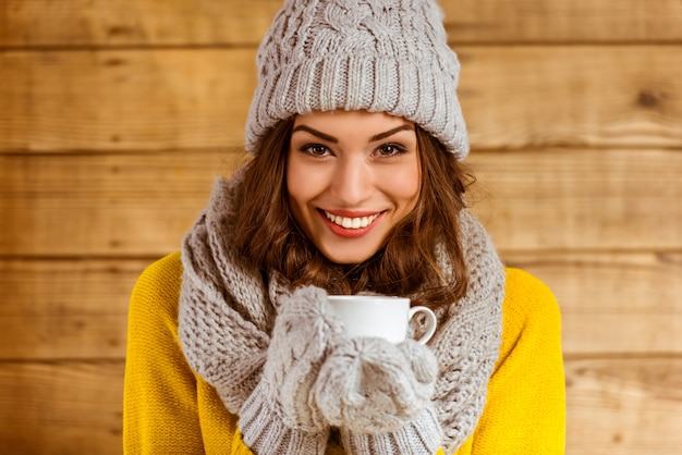 Bella ragazza con cappello e guanti, bere il tè.