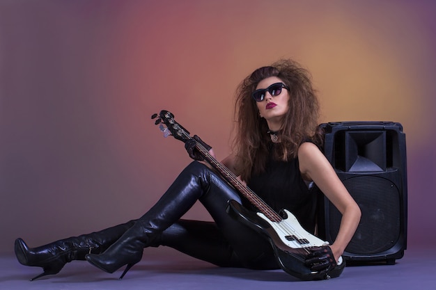 Bella ragazza con chitarra basso in abiti di pelle.