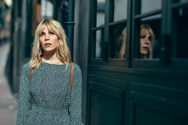 Bella ragazza con gli occhi azzurri che porta vestito che sta all&#39;aperto.