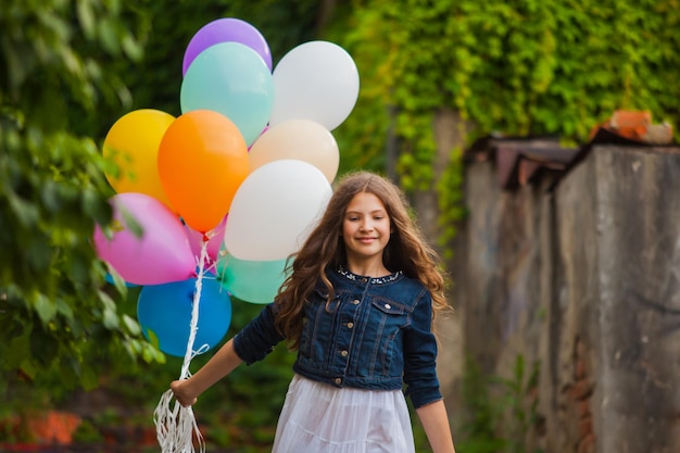 Bella ragazza con grandi palloncini colorati che cammina al piano di sotto nella città vecchia