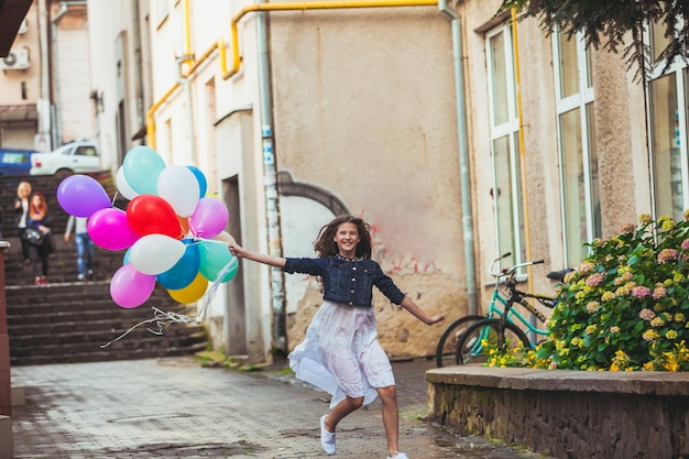 Bella ragazza con grandi palloncini colorati che camminano nella città vecchia