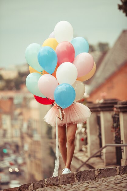 Bella ragazza con grandi palloncini in lattice colorati in posa per la strada di una città vecchia