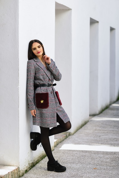 Bella ragazza con i capelli molto lunghi che indossa cappotto invernale e berretto all'aperto.