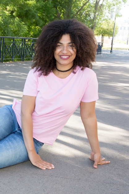 Bella ragazza con i capelli ricci con una maglietta rosa e blue jeans