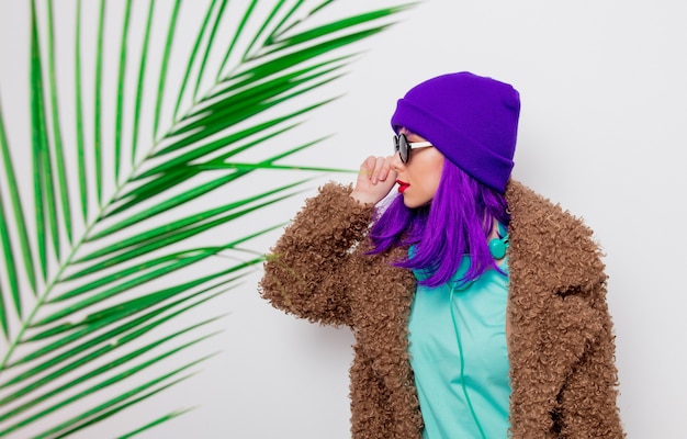 Bella ragazza con i capelli viola in giacca con foglia di palma.