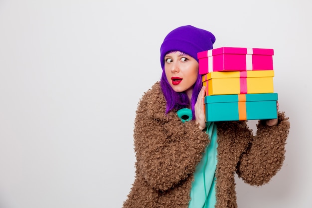 Bella ragazza con i capelli viola in giacca con scatole regalo per le vacanze.