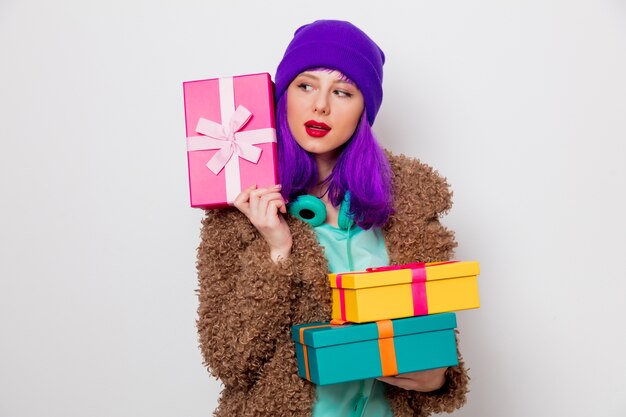 Bella ragazza con i capelli viola in giacca con scatole regalo per le vacanze.