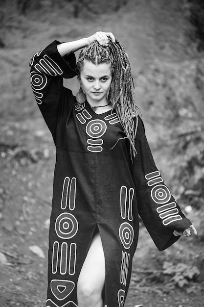 Bella ragazza con i dreadlocks vestita in stile hippie posa all'aperto