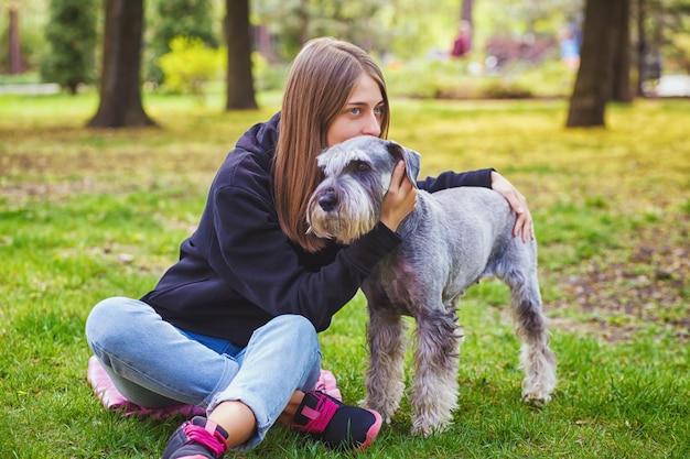 Bella ragazza con il suo cane Schnauzer al parco naturale