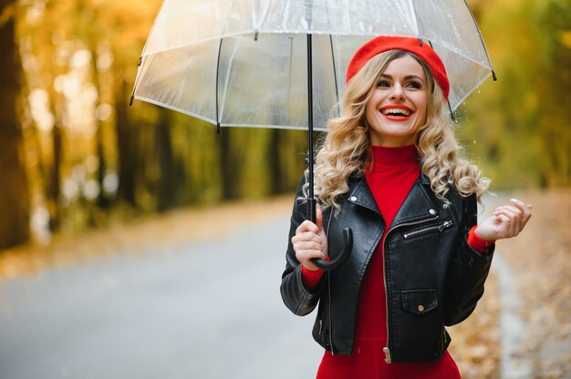 Bella ragazza con l'ombrello al parco d'autunno.