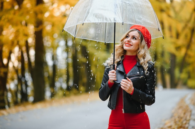 Bella ragazza con l'ombrello al parco d'autunno.