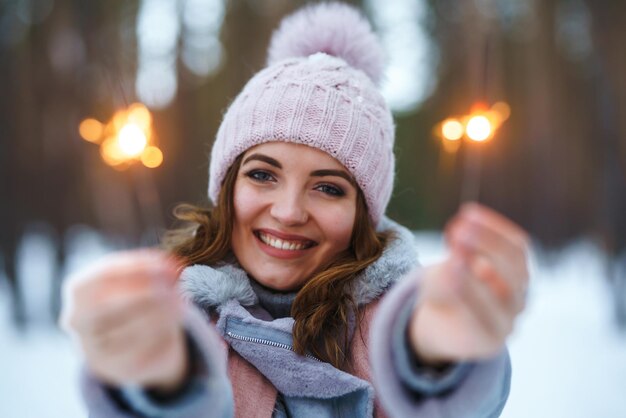 Bella ragazza con le stelle filanti in mano La ragazza vestita con un cappotto blu in una sciarpa cappello a maglia leggera