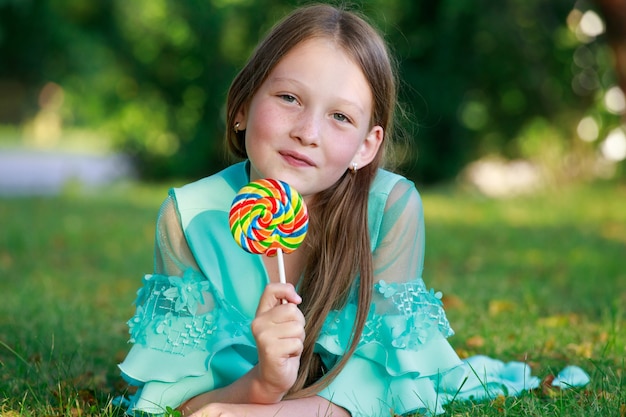 Bella ragazza con lecca-lecca colorato nel parco