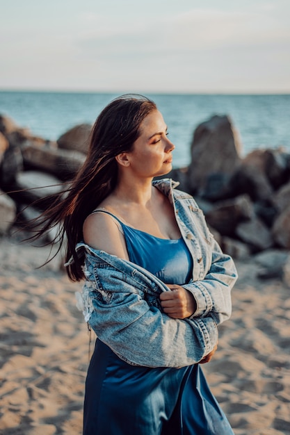 Bella ragazza con lunghi capelli scuri cammina sulla spiaggia la sera e si gode il tramonto.