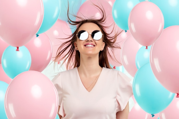 Bella ragazza con palloncini blu e rosa sulla parete rosa.