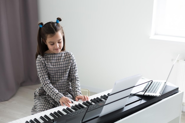 bella ragazza con ricciolo lounge che suona un pianoforte in appartamento