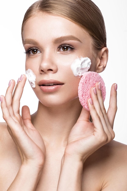 Bella ragazza con spugna e schiuma detergente e manicure francese. Viso di bellezza. Foto scattata in studio su sfondo bianco.