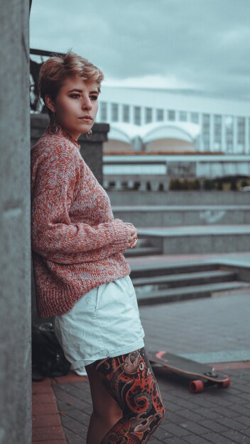 Bella ragazza con tatuaggi con longboard in città. Ha un tatuaggio tradizionale giapponese