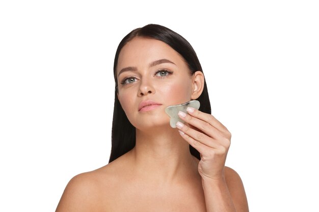 Bella ragazza con trucco naturale e pelle pulita Tiene in mano uno scrubber viso giada