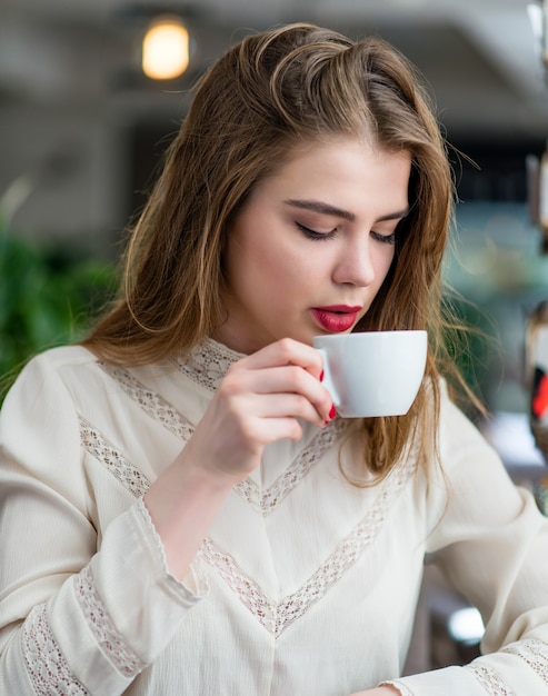 Bella ragazza con trucco professionale e acconciatura seduta nel ristorante.