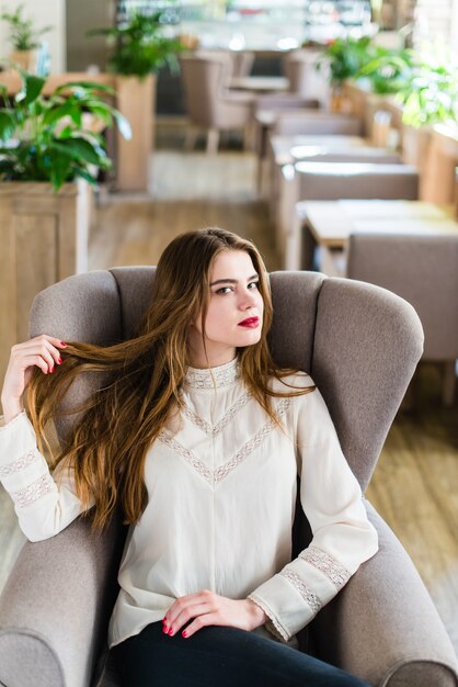 Bella ragazza con trucco professionale e acconciatura seduta nel ristorante.