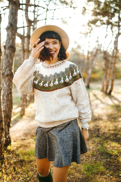 Bella ragazza con un bel sorriso al tramonto nella foresta La ragazza è vestita con un cappello