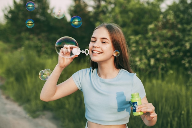 Bella ragazza con un bel sorriso soffia bolle di sapone