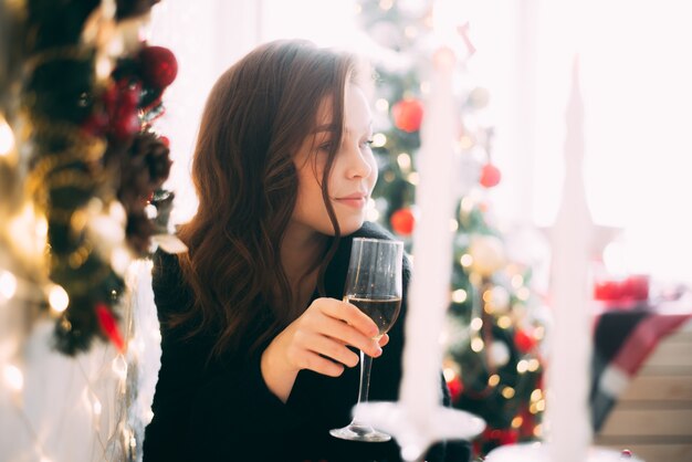 Bella ragazza con un bicchiere di champagne, sfondo di Natale e Capodanno